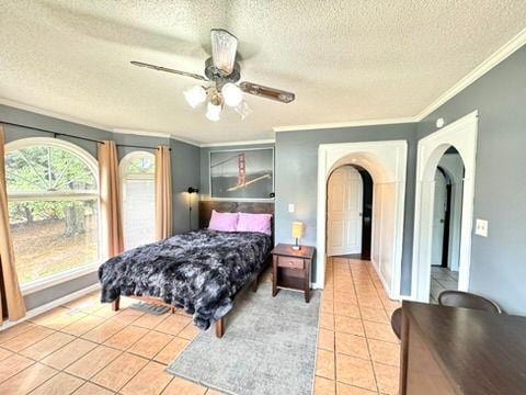 bedroom with a textured ceiling, ornamental molding, ceiling fan, and light tile patterned flooring