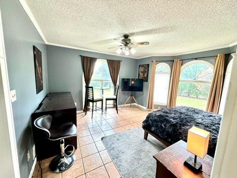 tiled bedroom featuring crown molding, ceiling fan, and a textured ceiling