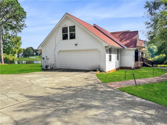 view of side of property with a garage, a water view, and a yard