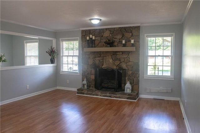 unfurnished living room with a stone fireplace, hardwood / wood-style flooring, ornamental molding, and a healthy amount of sunlight