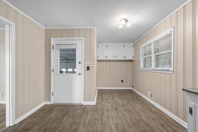 interior space with hardwood / wood-style flooring, wood walls, and crown molding