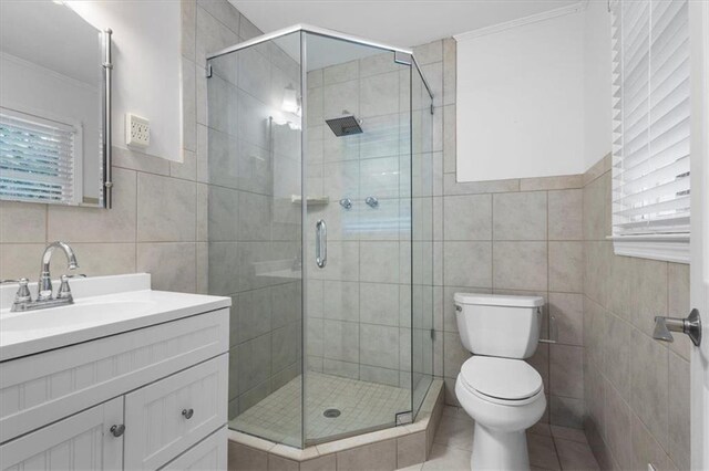 bathroom with walk in shower, tile patterned flooring, toilet, vanity, and tile walls