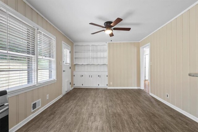 unfurnished living room with dark hardwood / wood-style floors, ceiling fan, built in features, and crown molding