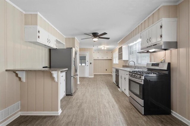 kitchen featuring white cabinetry, stainless steel appliances, range hood, wood-type flooring, and a breakfast bar