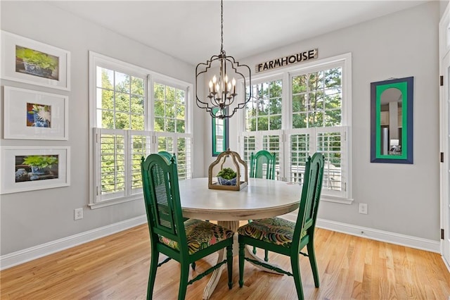 dining room with a chandelier, plenty of natural light, light wood-style floors, and baseboards