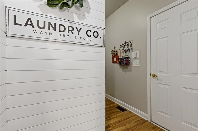 hallway with visible vents, baseboards, and wood finished floors