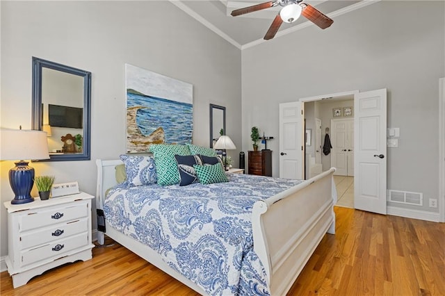 bedroom featuring light wood-type flooring, high vaulted ceiling, crown molding, and visible vents