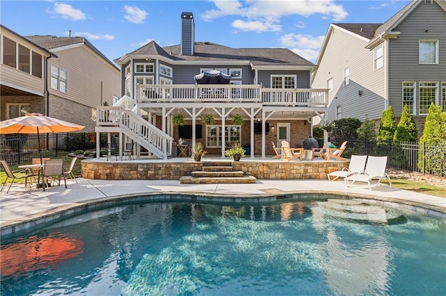 rear view of house with a fenced in pool, a patio, stairs, a deck, and fence