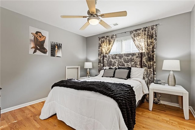 bedroom featuring light wood-style flooring, baseboards, a ceiling fan, and visible vents
