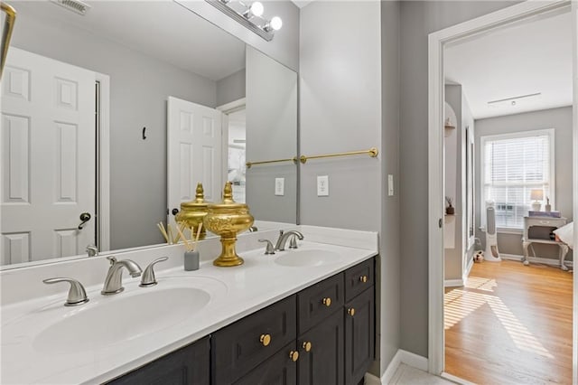 bathroom featuring double vanity, baseboards, and a sink