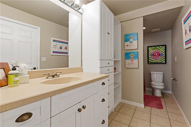bathroom with toilet, vanity, baseboards, and tile patterned flooring