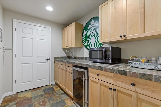 kitchen with baseboards, light brown cabinets, stainless steel microwave, beverage cooler, and stone finish flooring