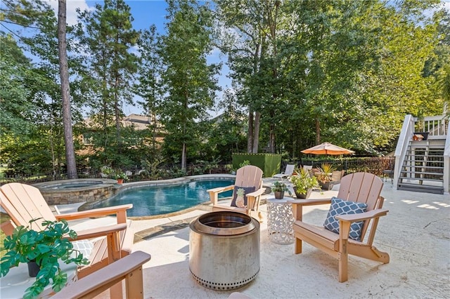 view of pool with a patio area, a pool with connected hot tub, fence, and stairs
