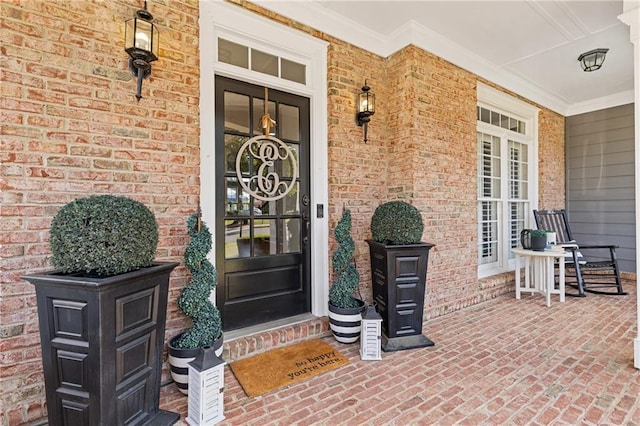 entrance to property featuring a porch and brick siding
