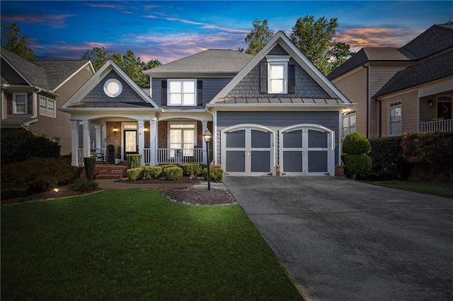 view of front facade with an attached garage, metal roof, covered porch, concrete driveway, and a standing seam roof