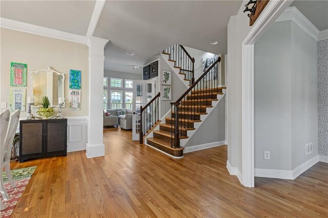 entryway with decorative columns, stairway, light wood-style floors, and baseboards
