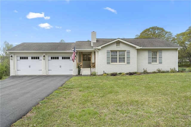 single story home featuring a chimney, driveway, a front lawn, brick siding, and a garage
