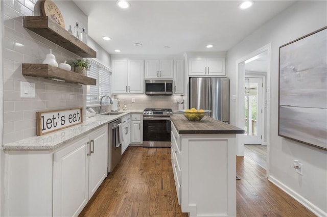 kitchen with dark wood-style floors, white cabinetry, open shelves, stainless steel appliances, and a sink