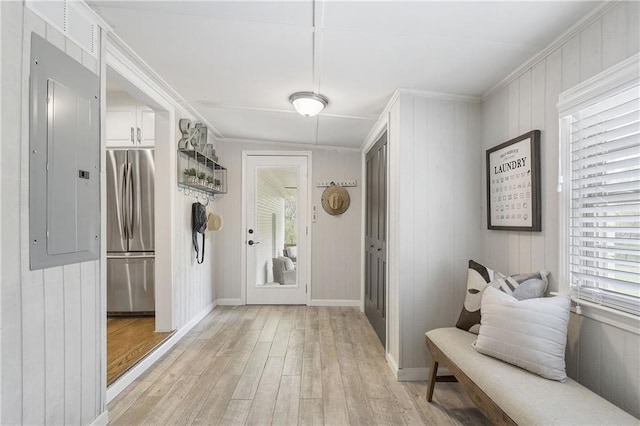 interior space with ornamental molding, baseboards, light wood-style floors, and electric panel