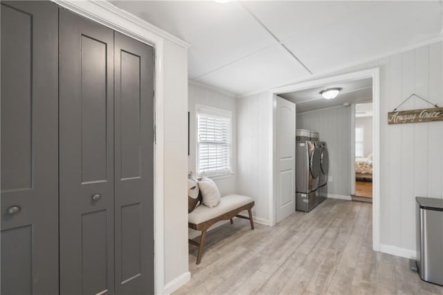 interior space featuring light wood finished floors, washing machine and dryer, baseboards, and ornamental molding