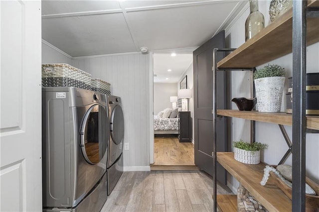 clothes washing area featuring laundry area, wood finished floors, crown molding, and washer and clothes dryer