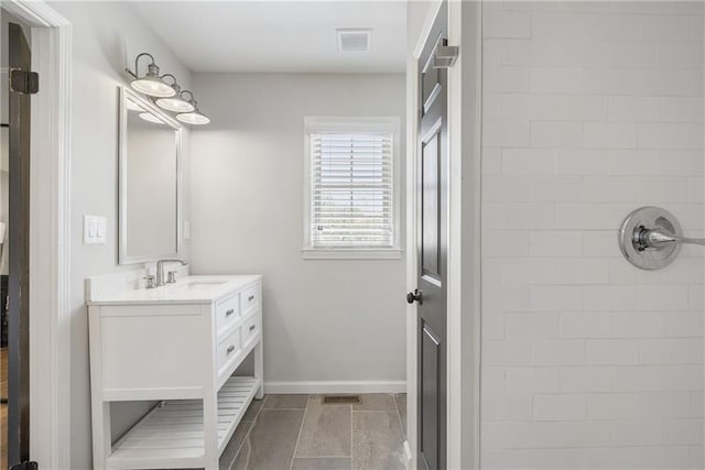 bathroom featuring vanity, visible vents, baseboards, and a tile shower
