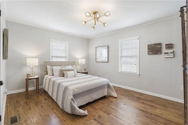 bedroom with wood finished floors, an inviting chandelier, multiple windows, and visible vents