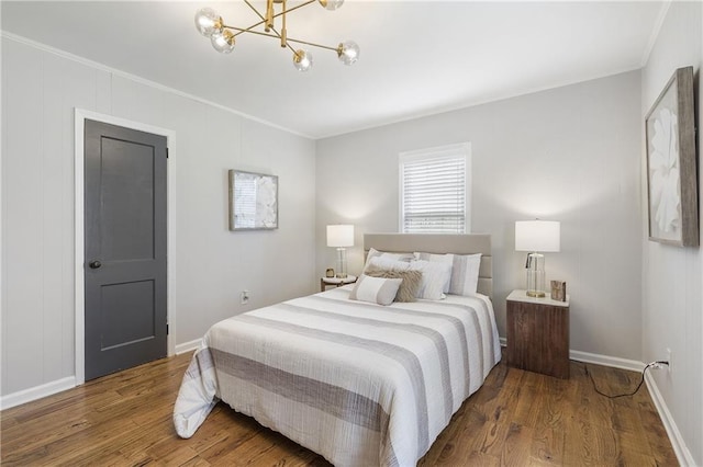 bedroom featuring a chandelier, crown molding, wood finished floors, and baseboards