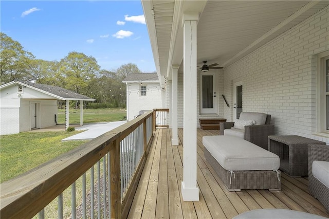 wooden terrace featuring a yard, a ceiling fan, and an outdoor structure