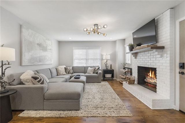 living area with baseboards, an inviting chandelier, a fireplace, and dark wood finished floors