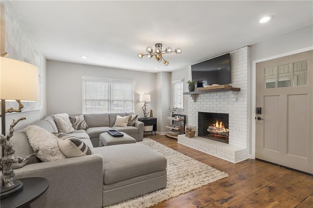 living area with a fireplace, dark wood finished floors, recessed lighting, baseboards, and a notable chandelier