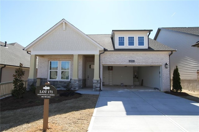 craftsman-style home with a garage, concrete driveway, brick siding, and a shingled roof