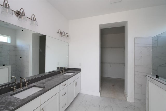 bathroom with double vanity, marble finish floor, a spacious closet, and a sink