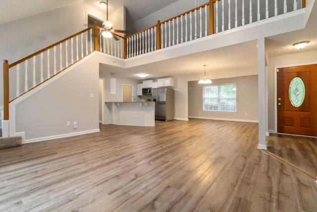 210 Riveredge Way, Mcdonough, GA 30252 - unfurnished living room with a towering ceiling, stairway, baseboards, wood finished floors, and a ceiling fan