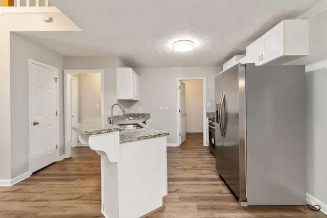 210 Riveredge Way, Mcdonough, GA 30252 - kitchen with stainless steel fridge, a sink, a peninsula, white cabinets, and light wood-style floors