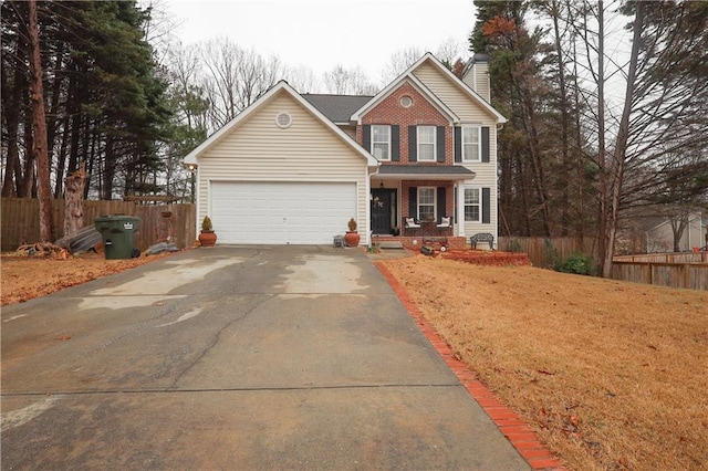 traditional home featuring brick siding, an attached garage, fence, a chimney, and driveway