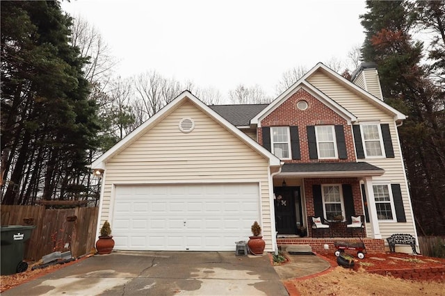 traditional-style home with fence, driveway, an attached garage, covered porch, and brick siding