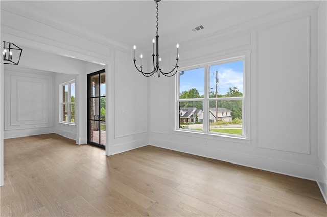 6120 Hutchins Dr, Buford, GA 30518 - unfurnished dining area featuring a chandelier, a decorative wall, and light wood-style flooring