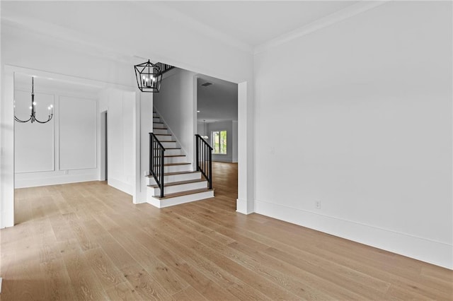6120 Hutchins Dr, Buford, GA 30518 - unfurnished living room featuring a chandelier, light wood-style floors, stairs, crown molding, and baseboards
