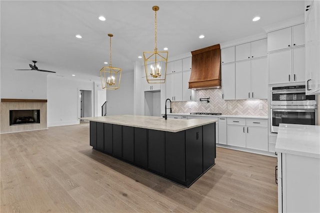 6120 Hutchins Dr, Buford, GA 30518 - kitchen featuring double oven, custom range hood, backsplash, a chandelier, and white cabinetry