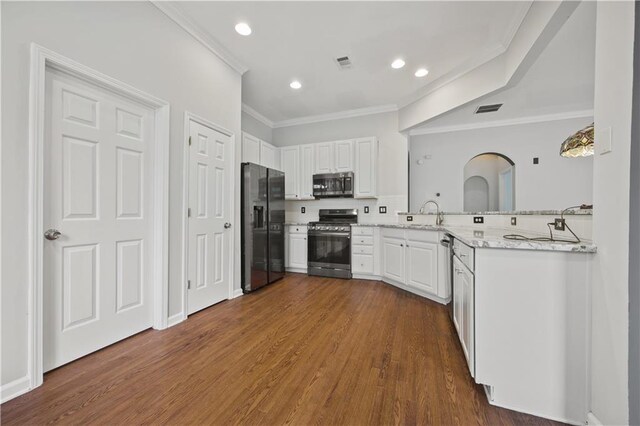 6329 Edgewater Cv, Fairburn, GA 30213 - kitchen featuring crown molding, dark wood finished floors, white cabinets, visible vents, and appliances with stainless steel finishes
