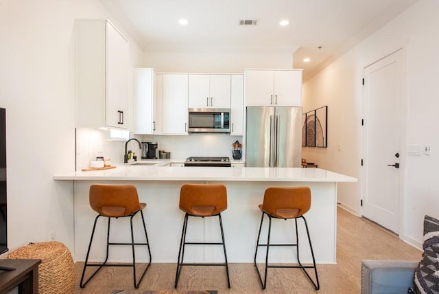 417 E College Ave Unit 102, Decatur, GA 30030 - kitchen featuring stainless steel appliances, a peninsula, a kitchen bar, a sink, and light countertops