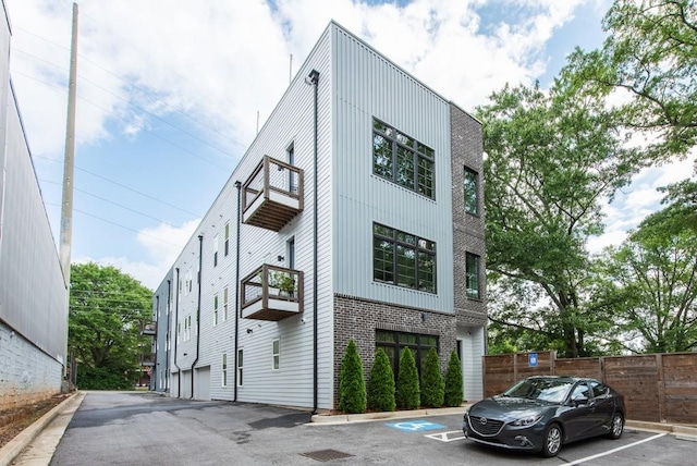417 E College Ave Unit 102, Decatur, GA 30030 - view of front of home featuring a balcony, uncovered parking, fence, and brick siding