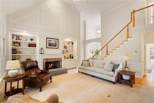 living area with crown molding, a high ceiling, arched walkways, built in shelves, and stairs