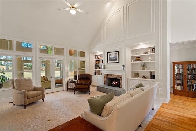 living room with a brick fireplace, a high ceiling, a wealth of natural light, and ceiling fan