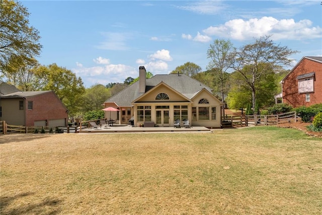 back of house featuring a lawn, fence, a chimney, and a patio area
