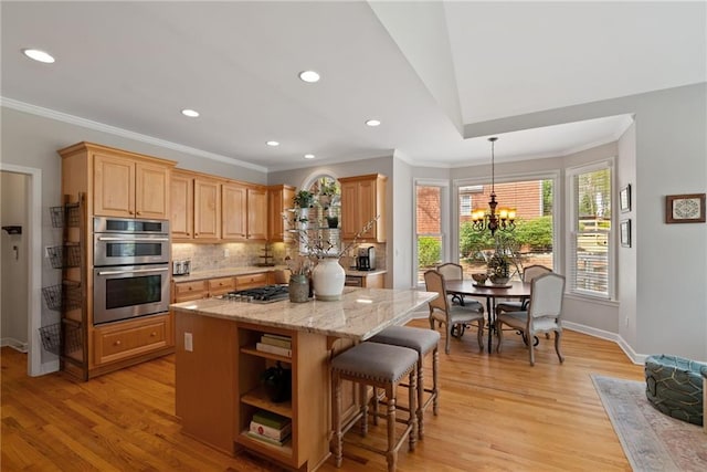 kitchen with crown molding, a kitchen island, tasteful backsplash, appliances with stainless steel finishes, and a notable chandelier