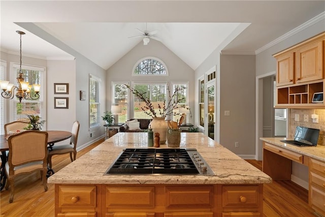 kitchen with pendant lighting, light stone counters, open floor plan, stainless steel gas stovetop, and light wood-style flooring
