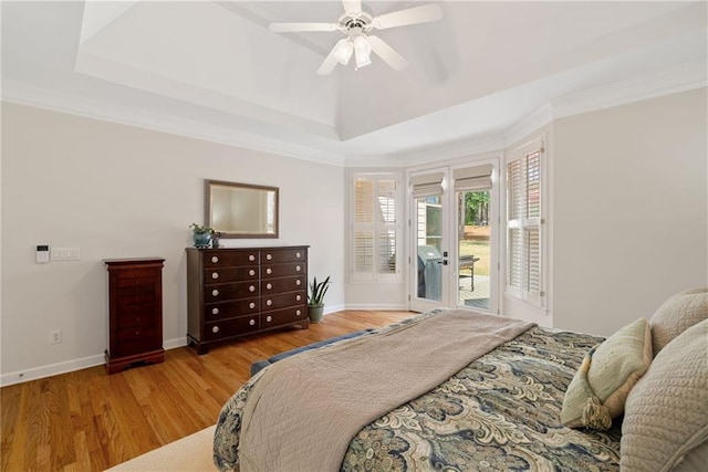 bedroom with access to outside, baseboards, wood finished floors, a tray ceiling, and ornamental molding