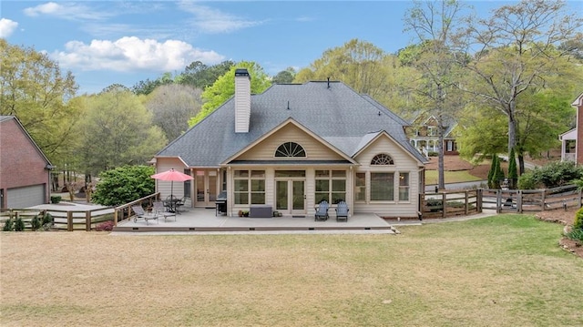 back of property featuring fence, a deck, french doors, a chimney, and a lawn